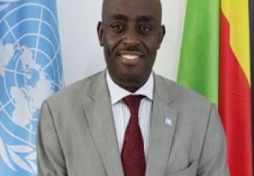 صورة رسمية لكريس مبورو وهو يقف بين علمي الأمم المتحدة وجمهورية الكونغو الديمقراطية.