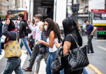 Plusieurs femmes et homme traversent la rue route dans une ville d’Argentine. Une des femmes porte un masque de protection.