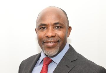 A man in a red tie smiles for the camera.
