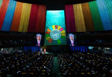 The hall of the general assembly lit up by the SDG colours and a projection of the secretary-general