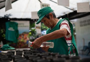 un hombre con sombrero riega las plantas
