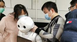 Des jeunes portant des masques de protection manipulent un robot.