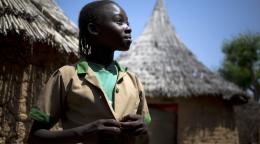 فتاة صغيرة تقف بفخر وتنظر إلى الأمام مباشرة.