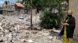 أمينة محمد، نائبة الأمين العام للأمم المتحدة، تقف إلى يمين الصورة بجانب بقايا ما يمكن أن يكون منازل.