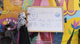 Una mujer señala una pizarra con información sobre los protocolos de seguridad relativos a la COVID-19. 