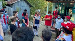 The Resident Coordinator, Mia Seppo, stands with a large group of people in masks stand outside in a circle. 
