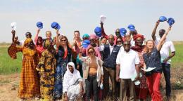 Le Coordonnateur résident des Nations Unies au Sénégal, Siaka Coulibaly, pose pour une photo en compagnie des members de l'équipe de pays des Nations Unies lors d'une mission de terrain dans les régions de Saint Louis et Matam, au nord du Sénégal. Les personnes photograhiées arborent un grand sourire et certaines d’entre elles lèvent leur casquette vers le ciel.