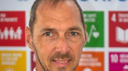 رجل يقف أمام لافتة عليها شعارات أهداف التنمية المستدامة