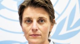 امرأة تقف أمام علم الأمم المتحدة.