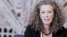 امرأة ترتدي سترة سوداء وتجلس وسط خلفية ضبابية.