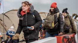 Tres personas caminan abrigadas, son refugiados ucranianos que llegan a la frontera polaca de Medyka.