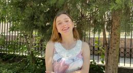 A woman in a white shirt and blonde hair smiles to the camera