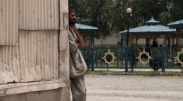 Мужчина стоит на улице, задумчиво прислонившись к углу здания