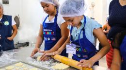 Two children roll a rolling pin on a baking sheet as they participate in a new UN programme