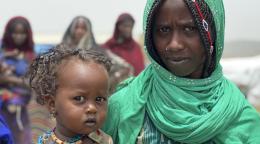 Женщина в зеленом платке держит ребенка на руках