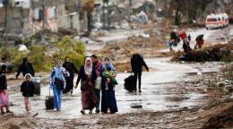  نازحون يسيرون من شمال غزة باتجاه الجنوب، بينما تتجه سيارات الإسعاف في الاتجاه الآخر.