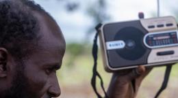 Мужчин держит на уровне головы и слушает карманное радио