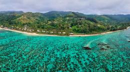 Зеленый берег острова Фиджи с зелоно-голубой прозрачной водой моря