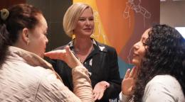Two women communicate to each other in sign language while a third woman listens