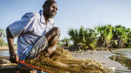 一位非洲男性坐在地上准备捕鱼