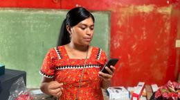 A woman in a bright red dress is looking at her phone.