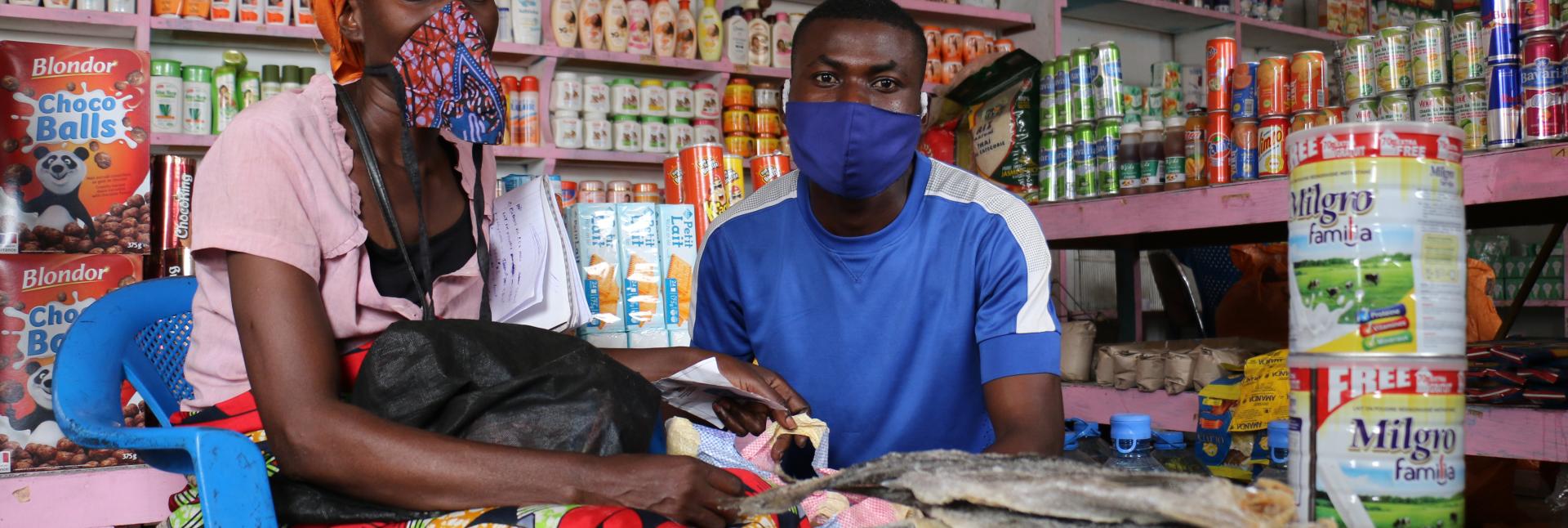 A woman and man wearing face mask sit inside their local market.