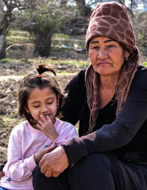 A woman sitting with her daughter in a backyard. 