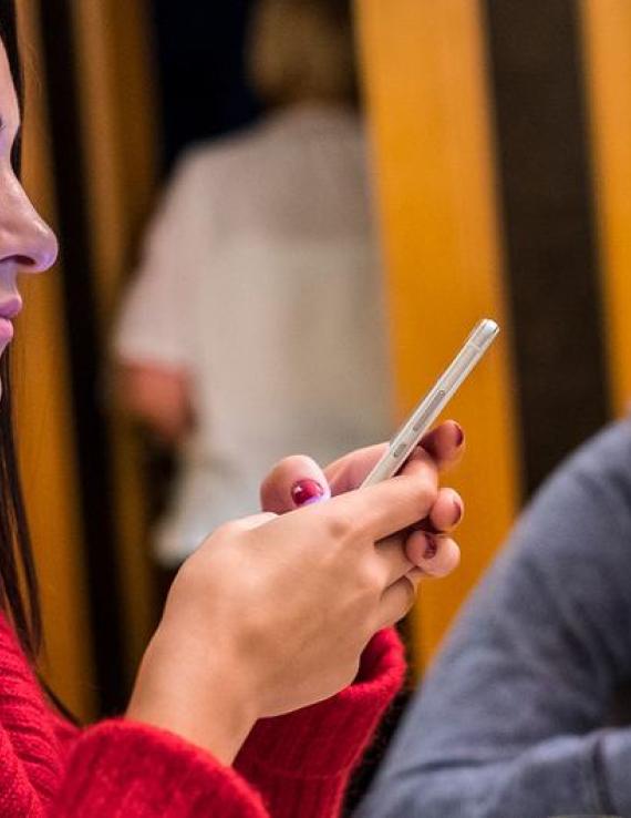 Young people look down and play on their phones.