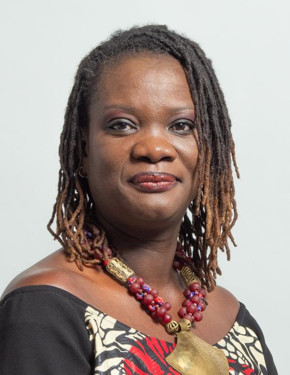 A woman in a colourful black and red dress with a necklace of big red beads around her neck.
