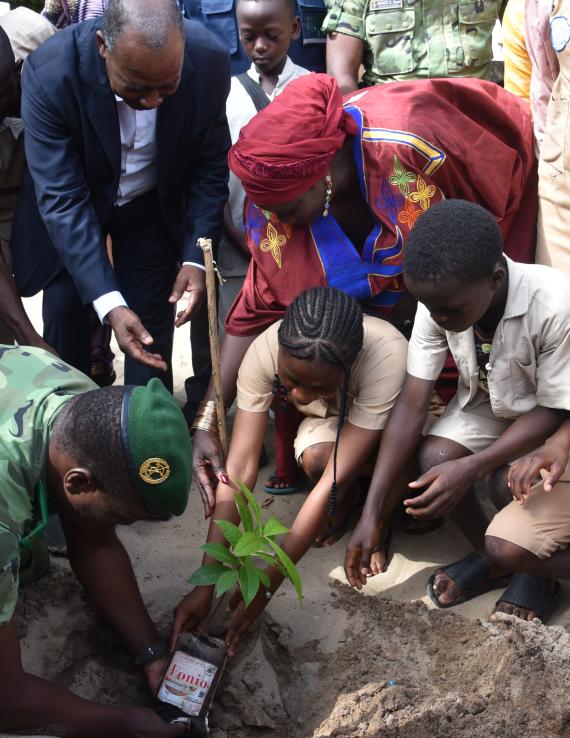 Un groupe de personnes plantant un arbre avec une jeune fille au milieu.