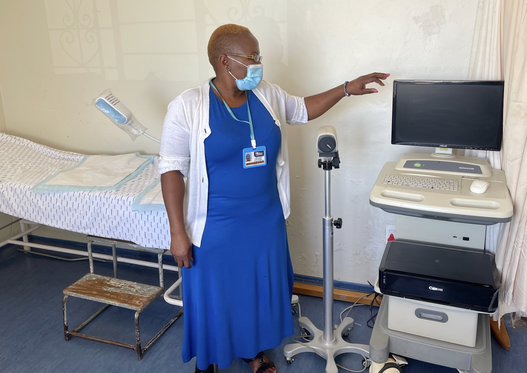 一名身穿蓝色衣服的医生站在医疗设备和病人的床边。