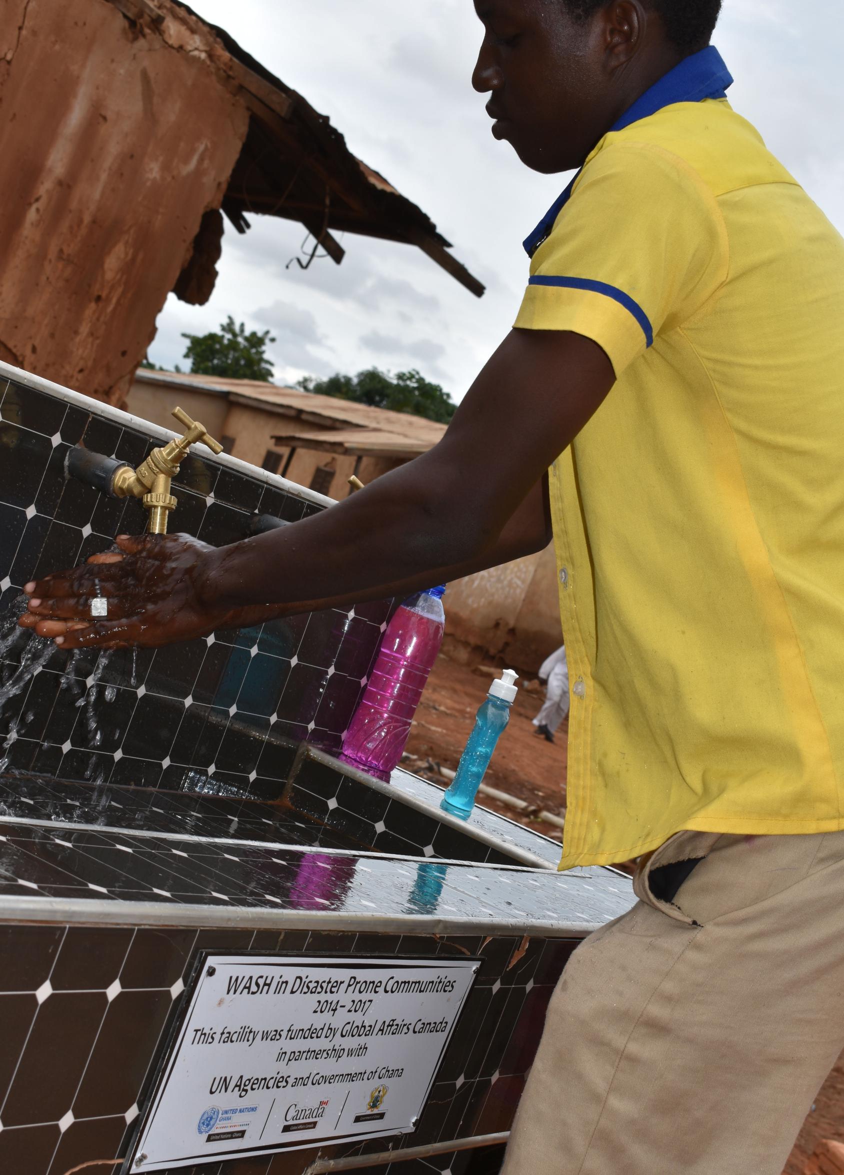 A resident of Ward K uses the handwashing station built for the community.