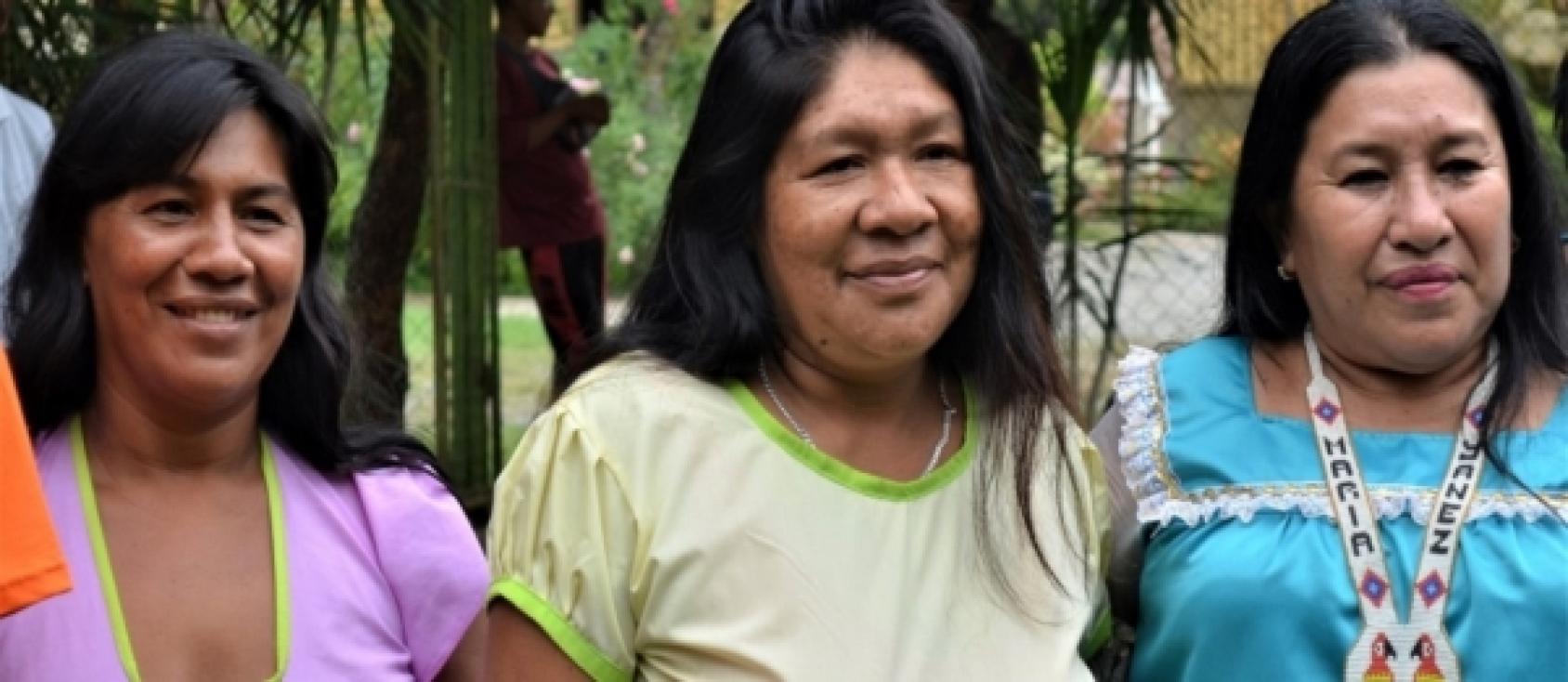 Gros plan sur trois femmes vêtues de hauts colorés et souriant à l'objectif.