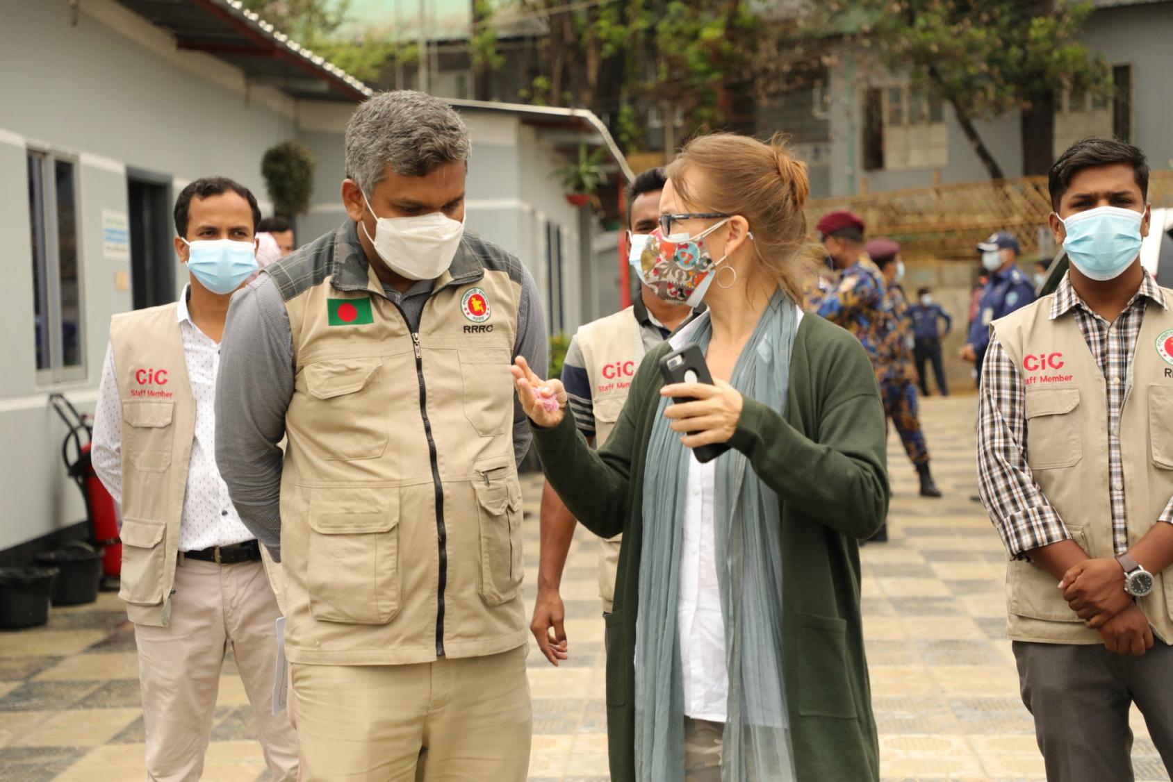 امرأة ورجل يرتديان كمامتين ويتحدثان في الهواء الطلق.