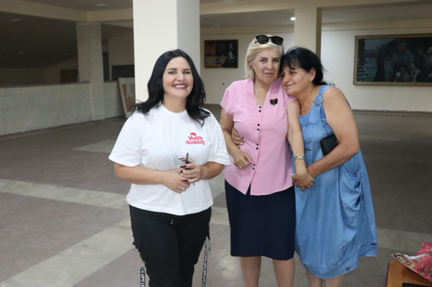 Three women stand close to each other and smile at the camera. 