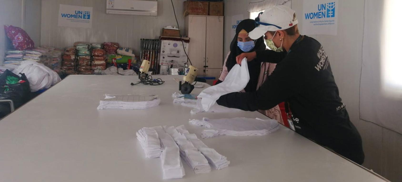 تعمل امرأتان على طاولة بيضاء كبيرة.