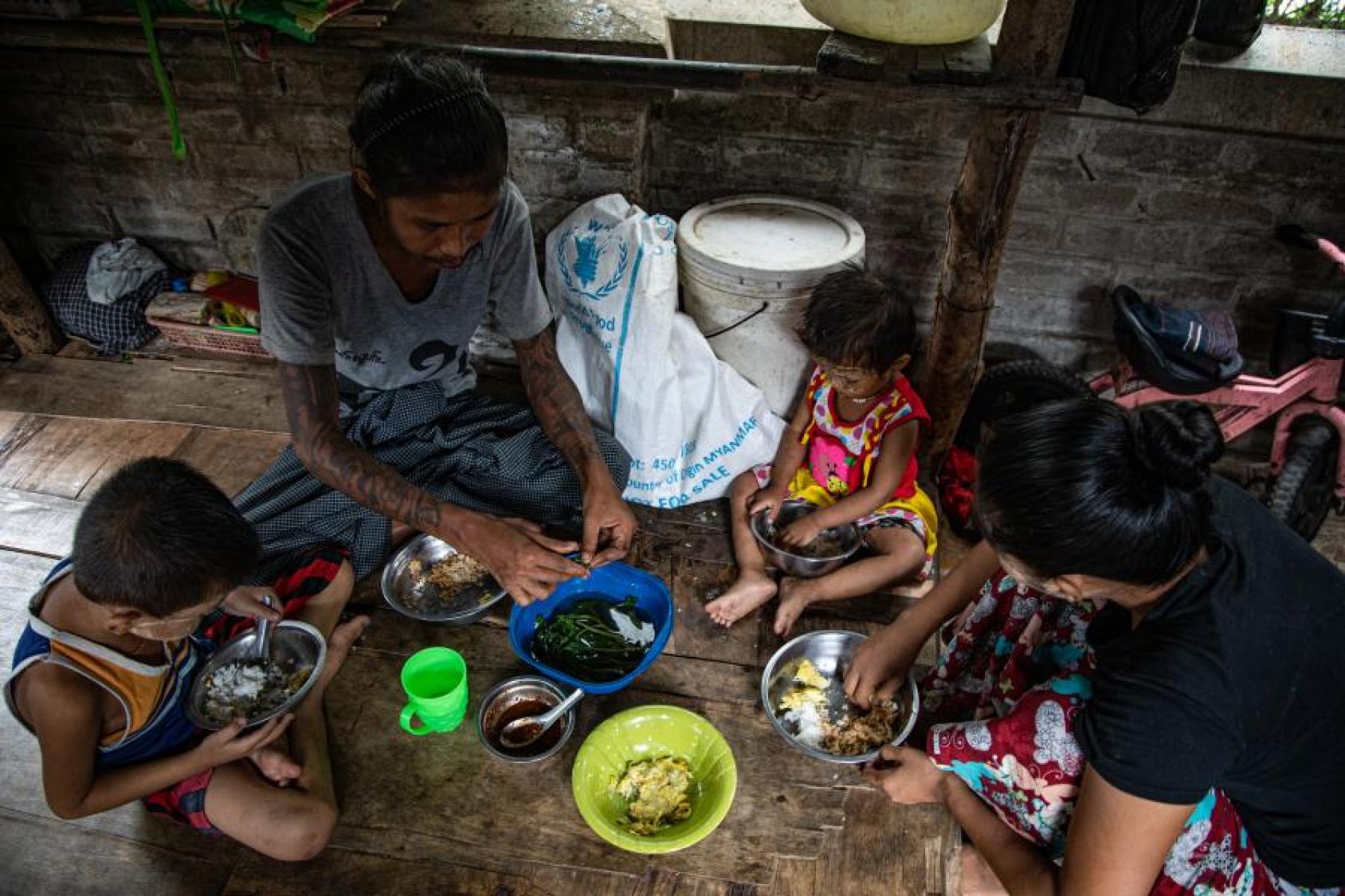 A family of four sit on the floor to have their dinner. 