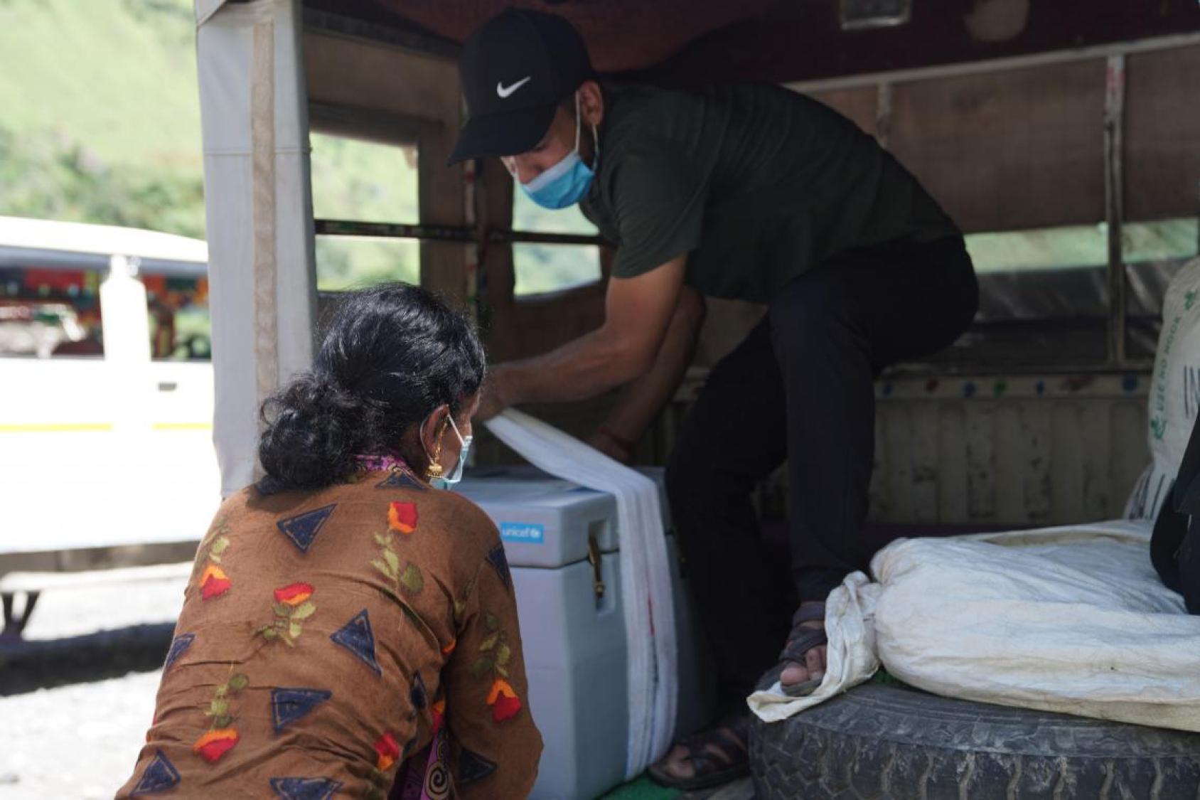 Two people unload a large box from a truck. 