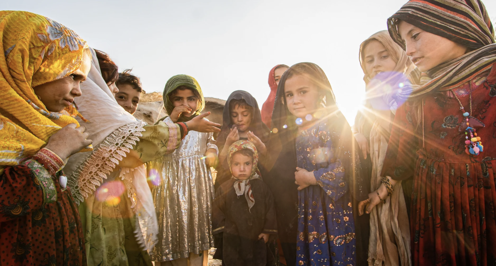 A group of girls stand in a circle with the light shining behind them. 