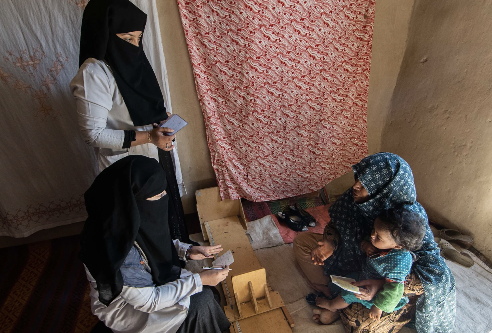 Three women and a boy speak over a small table. 