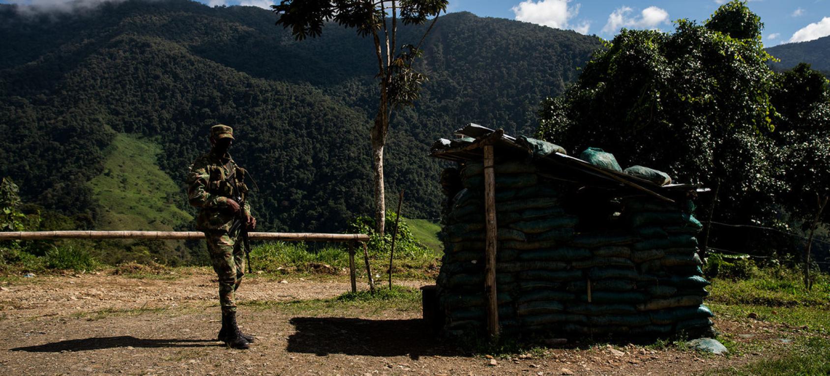 Un hombre con indumentaria militar resguarda el acceso a una estructura. 