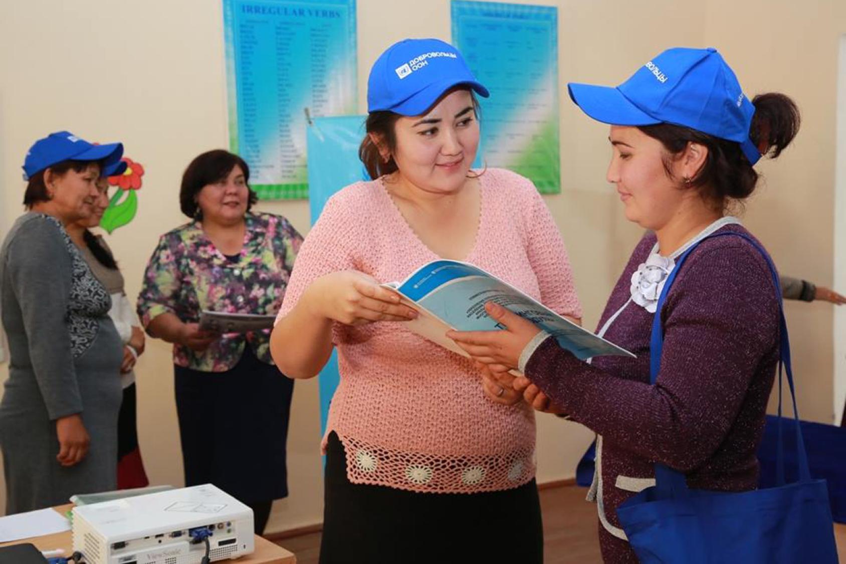 Women in blue hats look at a pamphlet.