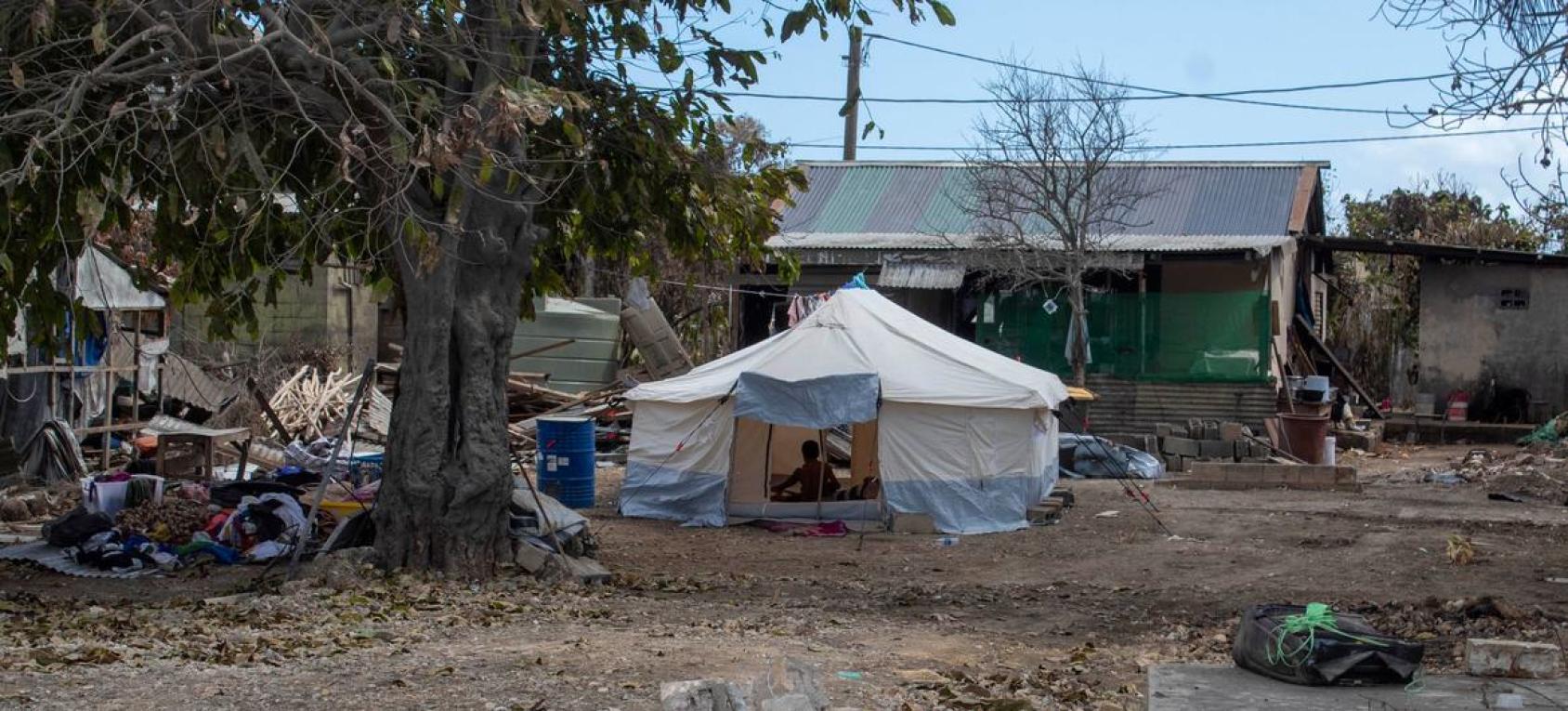 A temporary shelter is built near rubbles of a home. 