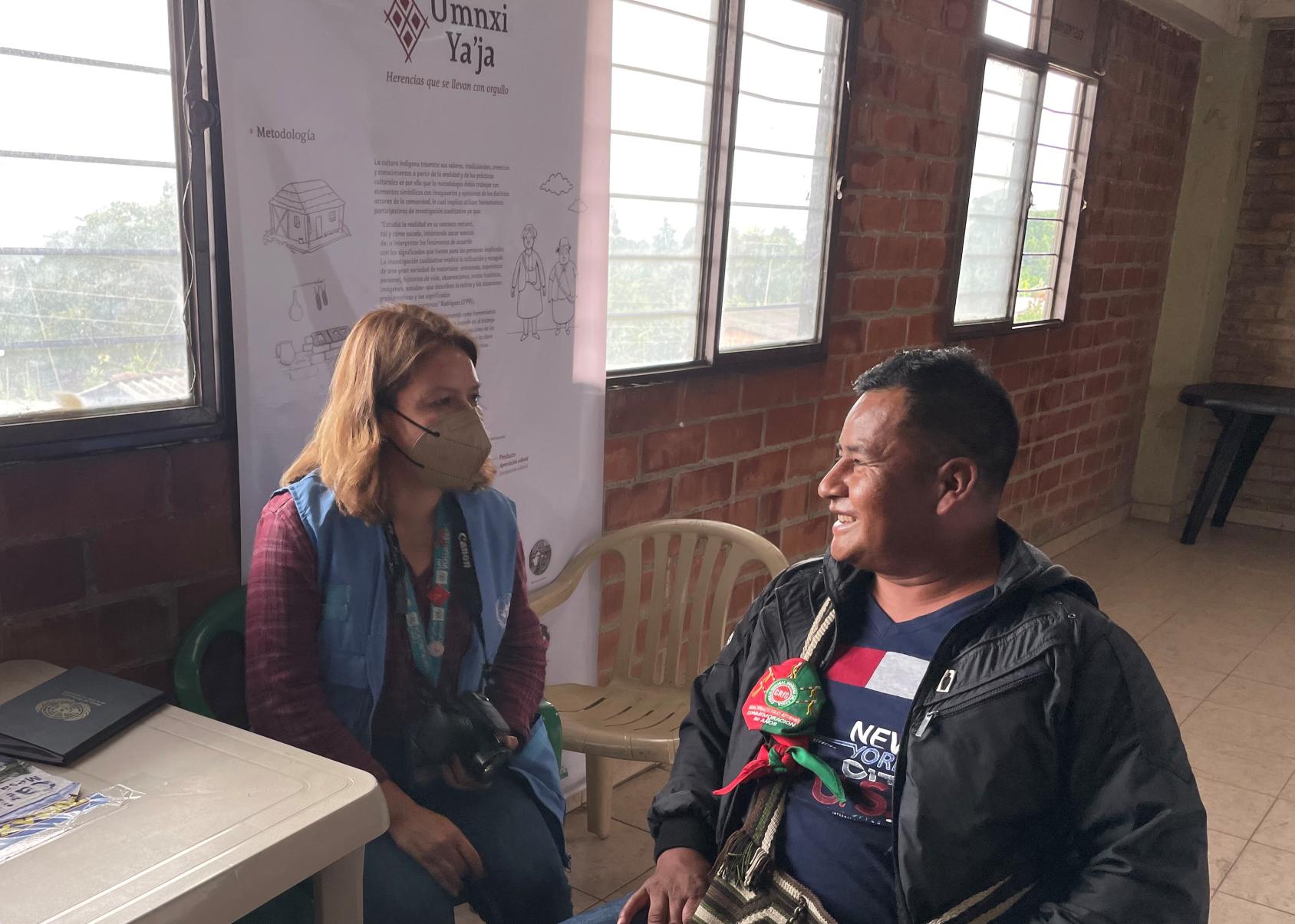 امرأة ترتدي سترة زرقاء ورجل في سترة سوداء يجلسان بجانب بعضهما البعض ويتبادلان أطراف الحديث.