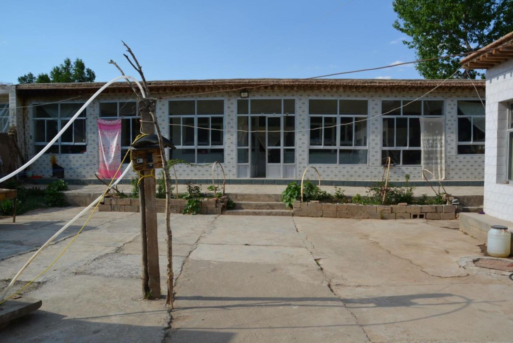 La vue d'un grand bungalow et d'une cour extérieure.