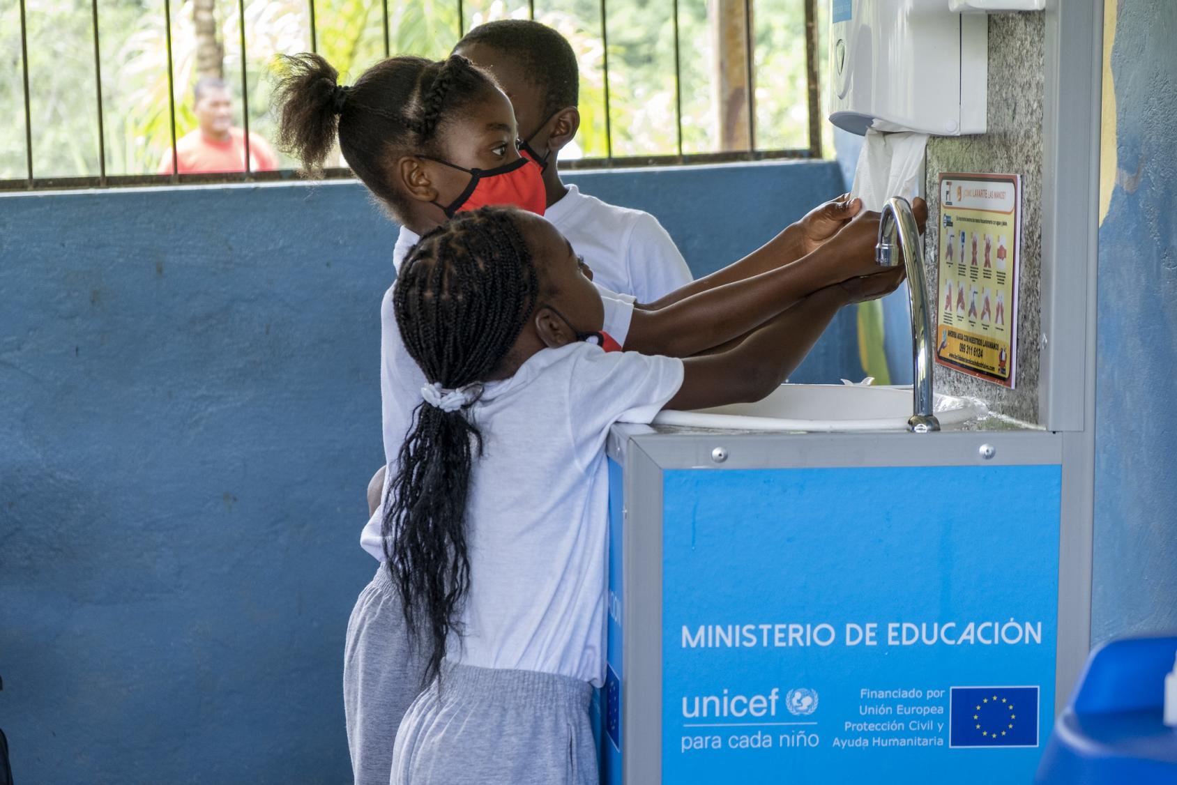 三个孩子在学校里洗手。