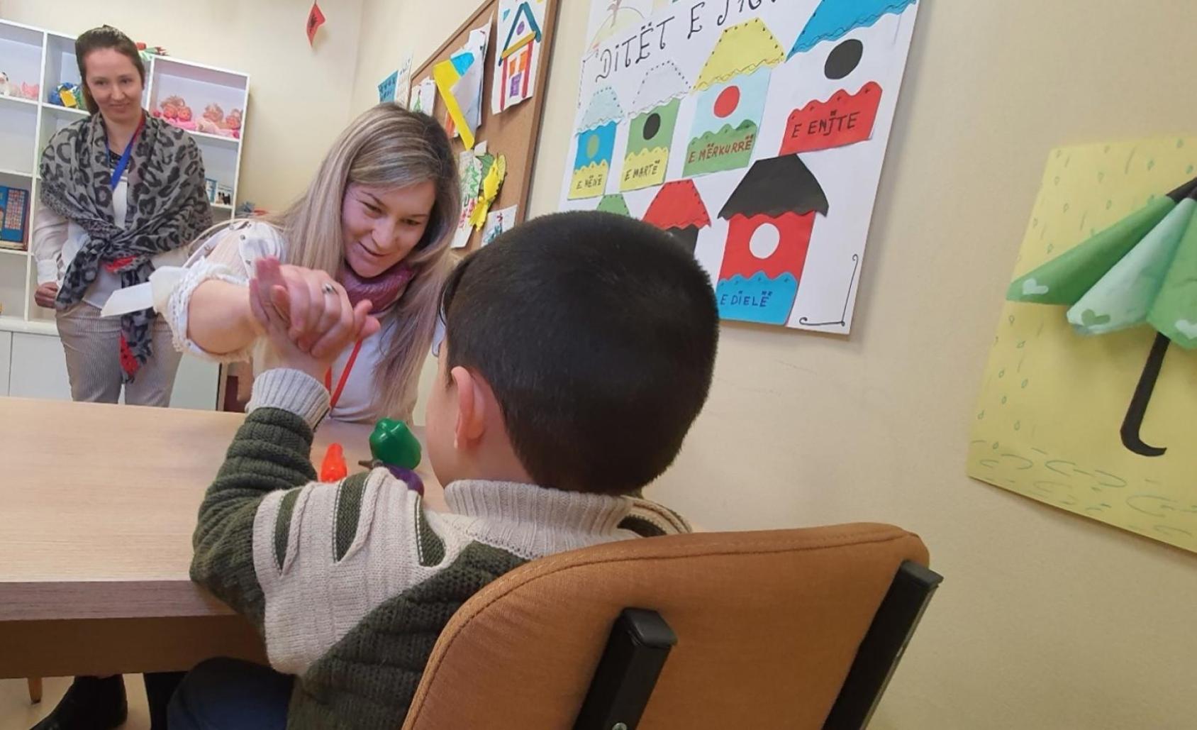 امرأة تلعب مع طفل فوق طاولة صغيرة، بينما تنظر إليها امرأة أخرى.