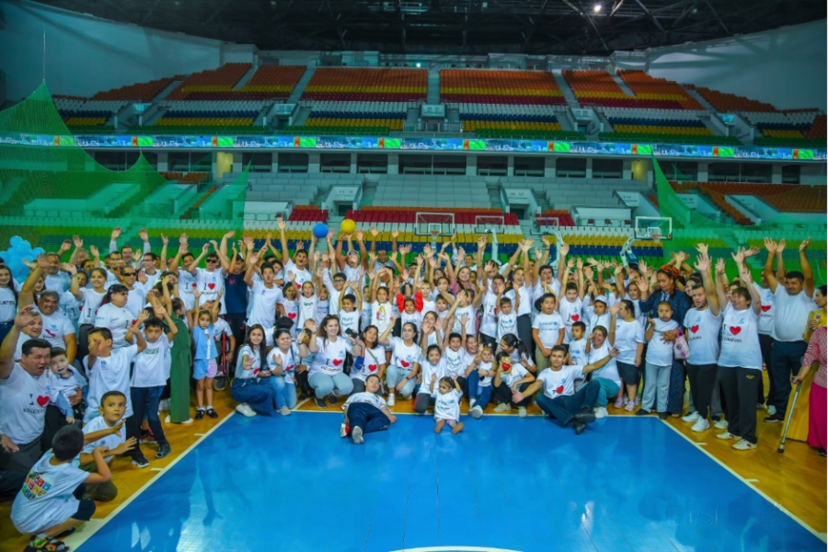 Una multitud de más de cien personas posa para la cámara en medio de un pabellón deportivo.