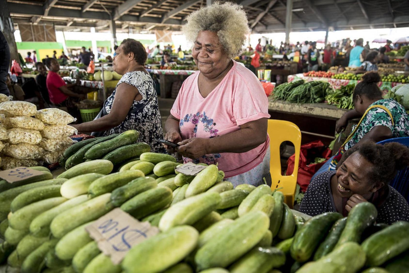 Pacific woman in the marketplace with a mobile phone