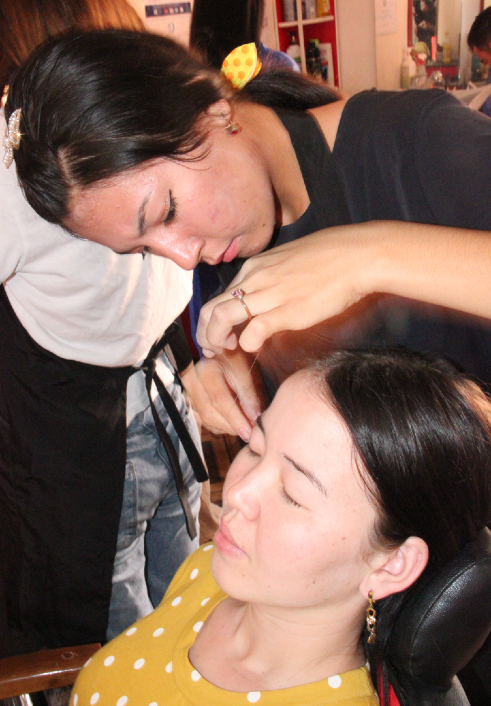 Woman threading another woman's eyebrow in Uzbekistan